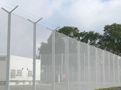 With barbed wire topping, a white PVC coated prison security fence is installed at a power station.
