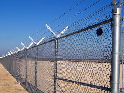 Chain link security fence combined with barbed wire used in large construction site.