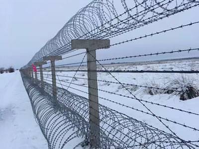 Concertina razor wires are installed in the snow.