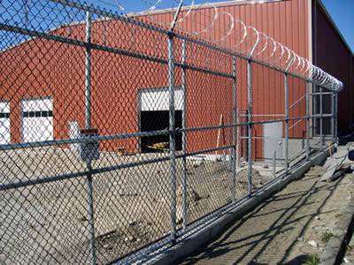 Chain link security fence combined with barbed wire and razor wire is used in factory.