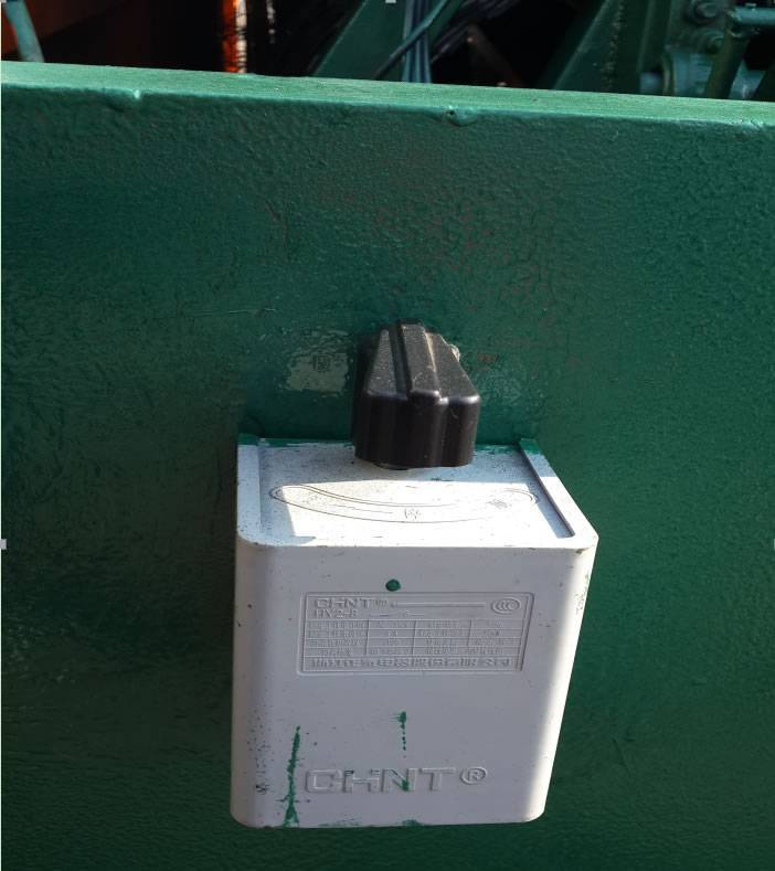 A white switch with black handle on a green razor wire trailer deployment.
