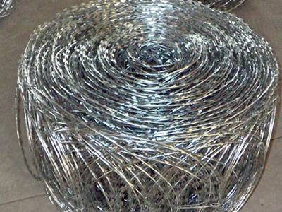 A roll of galvanized flat razor wire fence on the ground