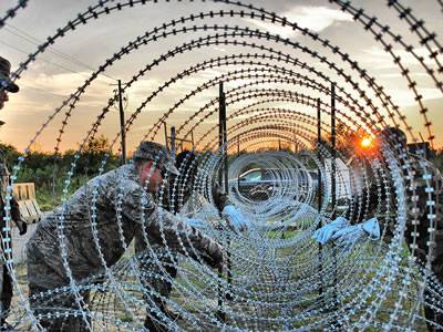 Several soldiers are fastening the razor wires.