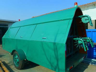A green razor wire trailer deployment with closed window and red caution light in a workshop.