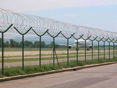 Barbed tapes are attached onto the welded wire fencing in the airport.