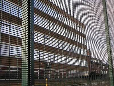 A dark green PVC coated prison security fencing is installed to surround the building.
