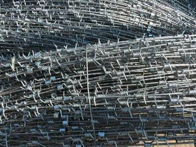 A section of barbed concertina wire is connected with clips and each twist barb has four spikes.