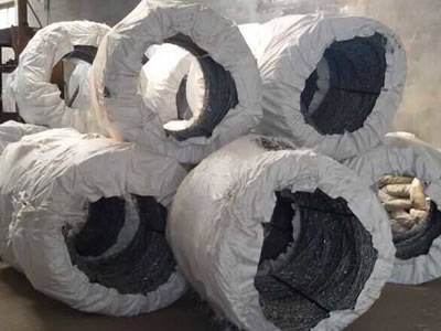 Many coils of concertina barbed wire are packed with white PP woven bag in workshop.