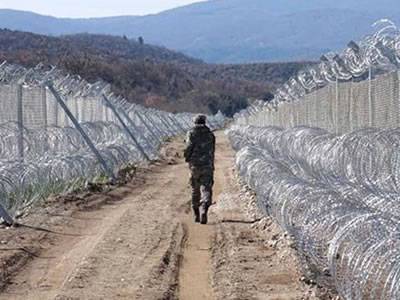 A soldier is patrolling and surrounding is installed with concertina razor coils.