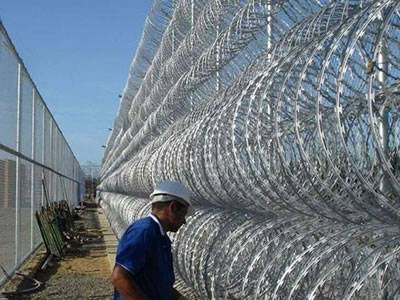Concertina razor wires are installed on the prison wall.