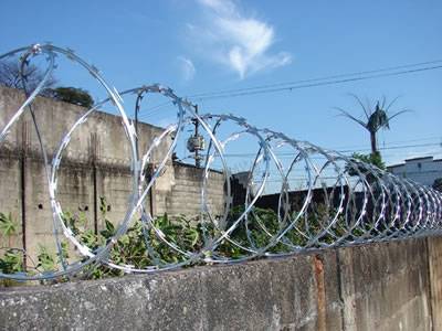 A line of concertina razor wire is installed on the concrete wall.