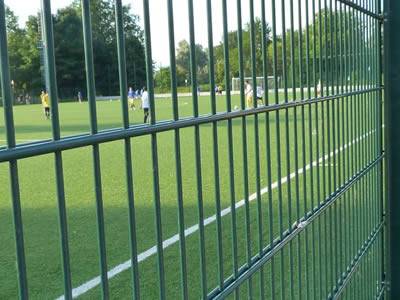 A dark green PVC coated welded double wire fence is installed at a football field.