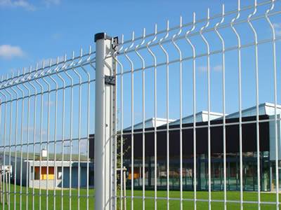 A white PVC coated welded wire 3D security fence is installed on the grassland.