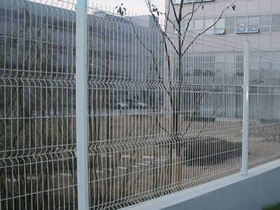 A white 4-curve PVC coated welded wire 3D security fence is installed between the residence and a road.