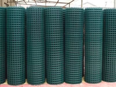 Many rolls of PVC welded mesh in dark green are placed in workshop.
